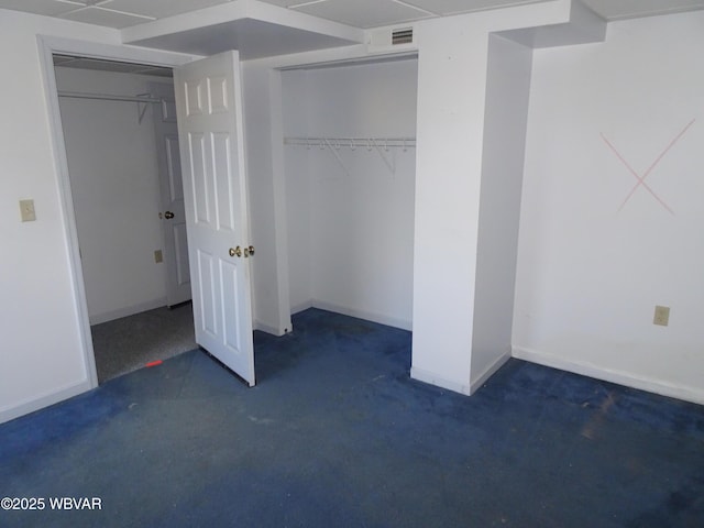 unfurnished bedroom with dark colored carpet and a closet