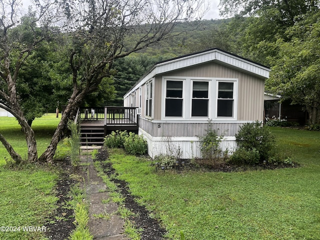 view of property exterior with a lawn and a wooden deck