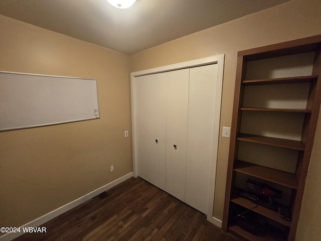 unfurnished bedroom with dark hardwood / wood-style flooring and a closet