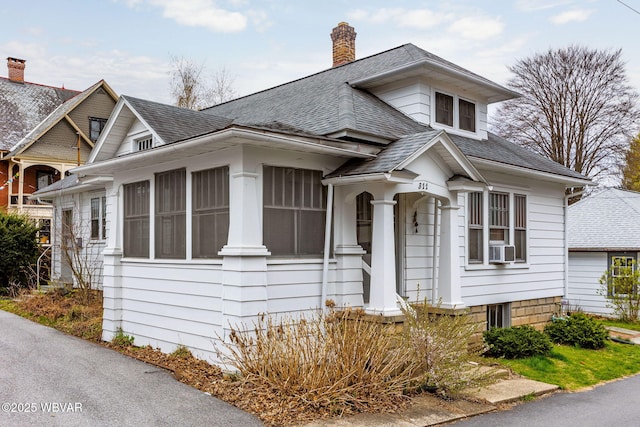 bungalow-style house with a chimney and roof with shingles