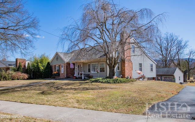 view of front facade featuring a front lawn, an outbuilding, a garage, and aphalt driveway