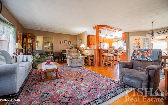 living room with a notable chandelier, plenty of natural light, and wood finished floors