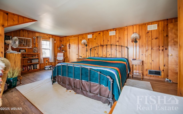 bedroom with lofted ceiling, wood finished floors, and visible vents