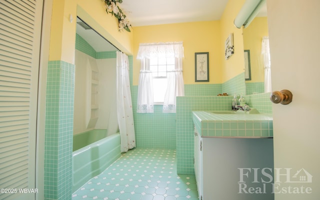 bathroom with vanity, shower / bathtub combination with curtain, a wainscoted wall, tile walls, and tile patterned floors