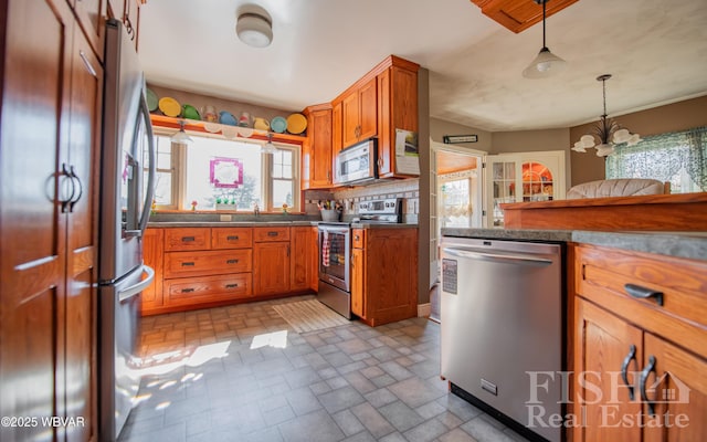 kitchen featuring hanging light fixtures, decorative backsplash, brown cabinets, and stainless steel appliances