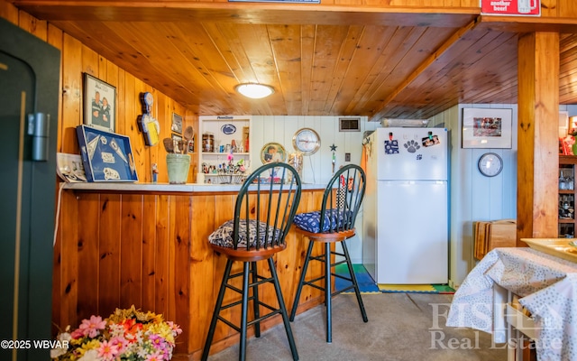 kitchen featuring wood walls, wooden ceiling, black fridge, and freestanding refrigerator