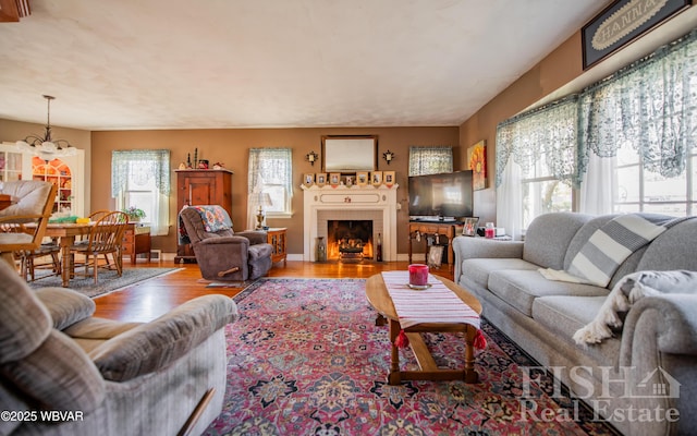 living area with a fireplace with flush hearth, baseboards, and wood finished floors