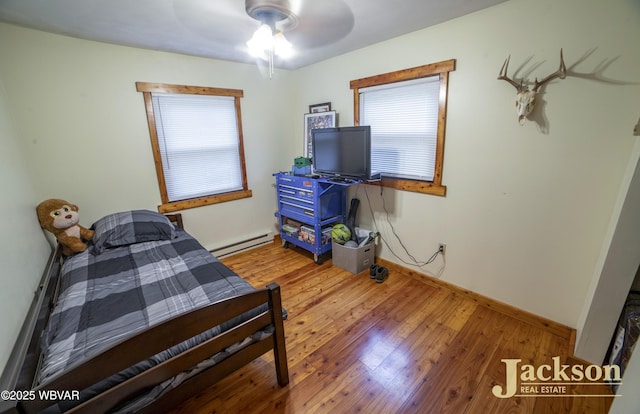 bedroom with ceiling fan, light hardwood / wood-style floors, and baseboard heating