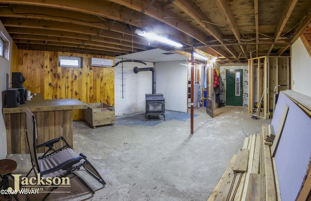 basement featuring washer / dryer, a wood stove, and wooden walls