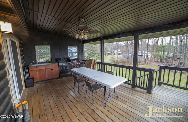 wooden deck with an outdoor kitchen, ceiling fan, and a grill