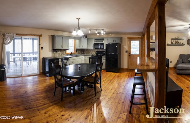 dining room with sink, wood-type flooring, and ceiling fan with notable chandelier