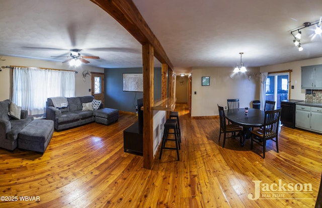 living room with wood-type flooring, ceiling fan with notable chandelier, and a healthy amount of sunlight