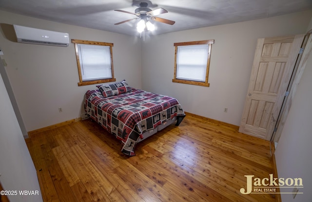 bedroom featuring wood-type flooring, an AC wall unit, and ceiling fan