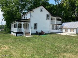 back of house featuring a lawn and an outbuilding