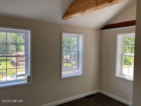 empty room featuring dark wood finished floors, vaulted ceiling, and baseboards