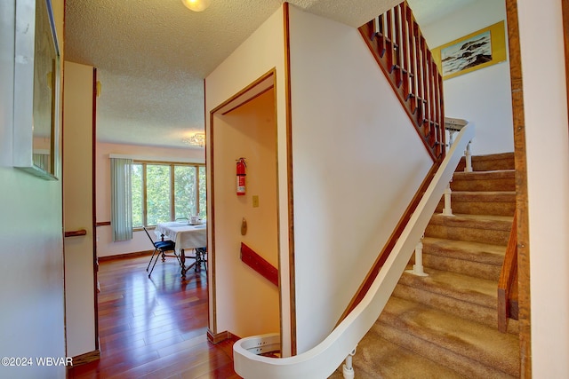 stairs featuring a textured ceiling and hardwood / wood-style flooring