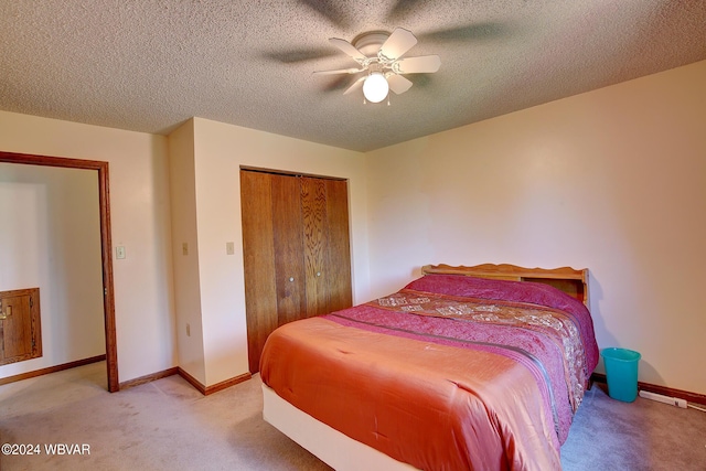 bedroom with ceiling fan, a closet, light colored carpet, and a textured ceiling