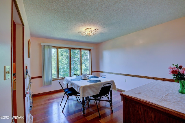 dining space with hardwood / wood-style floors and a textured ceiling