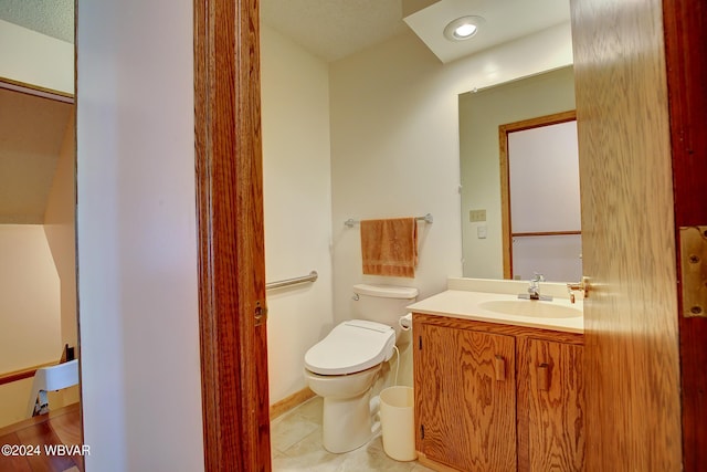 bathroom featuring tile patterned flooring, a textured ceiling, vanity, and toilet