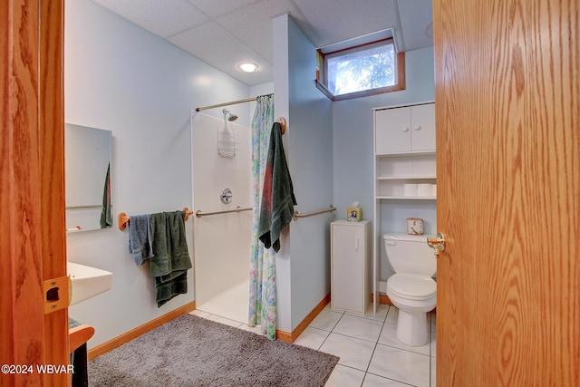 bathroom with tile patterned floors, curtained shower, a drop ceiling, and toilet