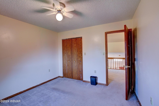 unfurnished bedroom with ceiling fan, a closet, light carpet, and a textured ceiling