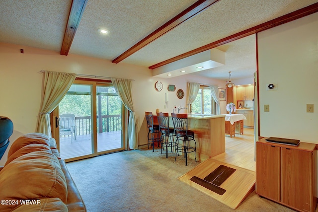 living room featuring beamed ceiling, light colored carpet, and a textured ceiling