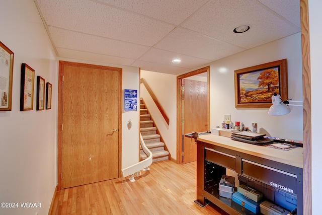 interior space featuring a paneled ceiling and light hardwood / wood-style floors