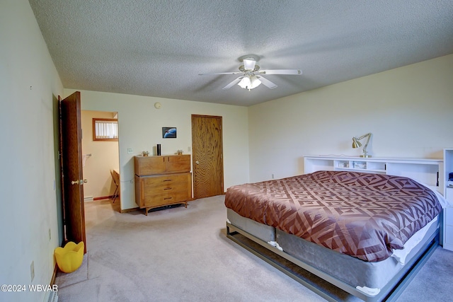 bedroom with ceiling fan, light colored carpet, and a textured ceiling