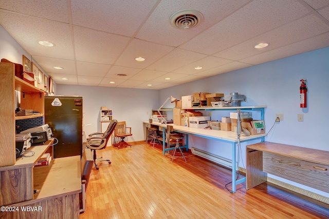 office area with a paneled ceiling and light hardwood / wood-style flooring