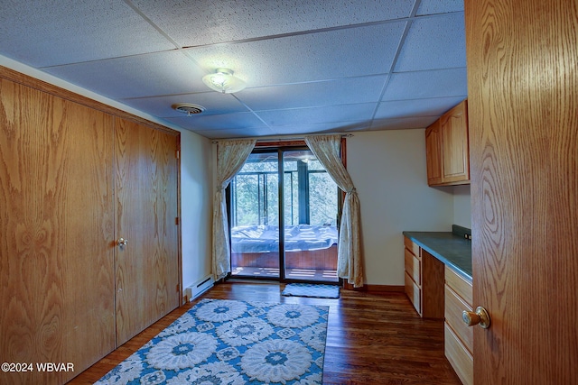 kitchen with a drop ceiling, dark hardwood / wood-style floors, and a baseboard heating unit