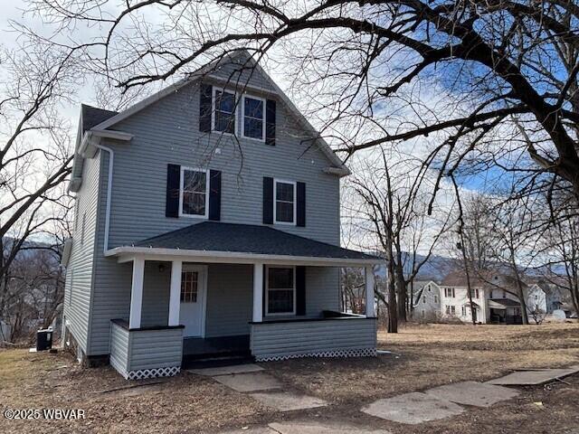 american foursquare style home with covered porch and central AC unit