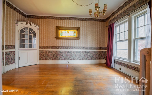 spare room featuring hardwood / wood-style floors, ornamental molding, and a chandelier