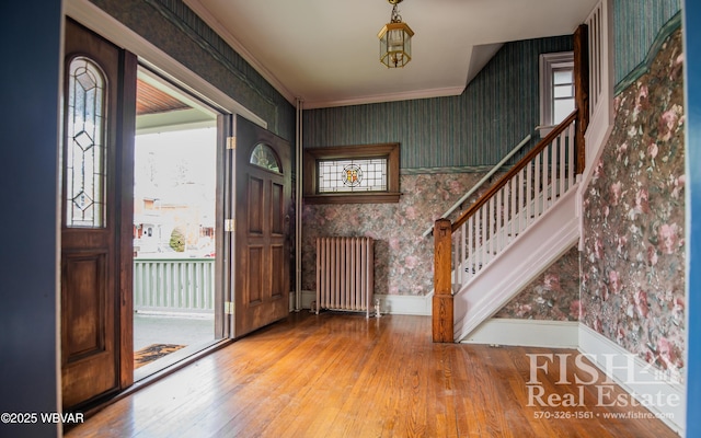 foyer entrance featuring radiator, hardwood / wood-style floors, an inviting chandelier, and ornamental molding