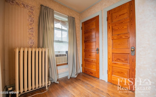 corridor featuring radiator, light hardwood / wood-style flooring, and cooling unit