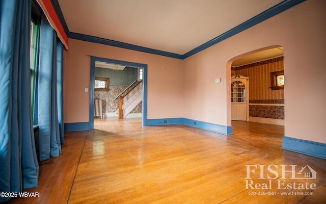 spare room with plenty of natural light, wood-type flooring, and ornamental molding