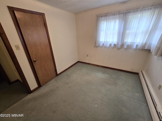 unfurnished bedroom with a baseboard heating unit, light carpet, a textured ceiling, and baseboards