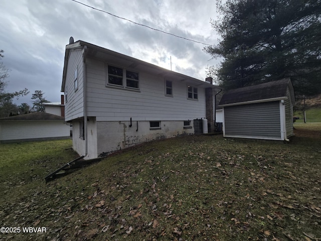 back of property featuring an outbuilding, a lawn, and a chimney