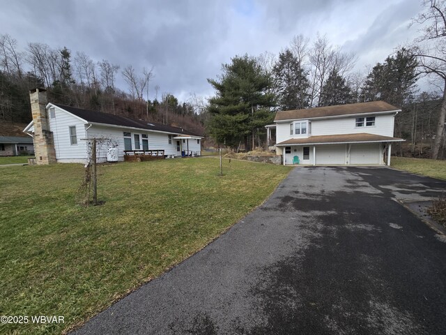 view of front of home featuring a garage, driveway, a front lawn, and a chimney