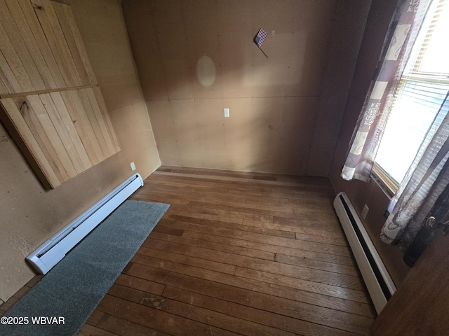 empty room featuring baseboard heating and dark wood-type flooring