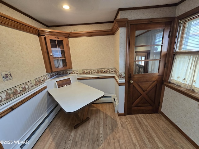 dining area with crown molding, a baseboard radiator, and hardwood / wood-style flooring