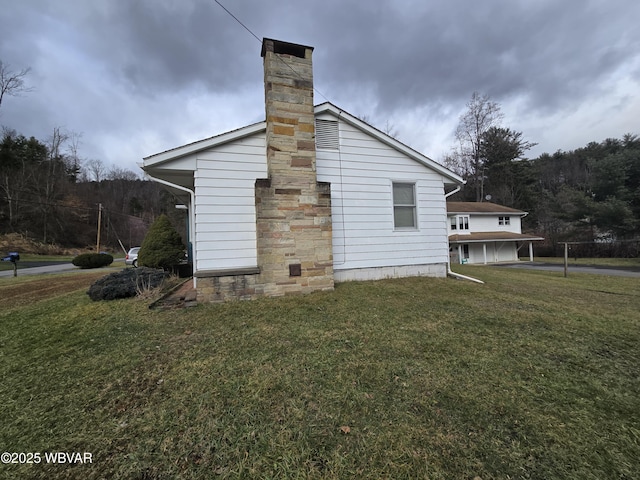 view of side of home featuring a chimney and a lawn