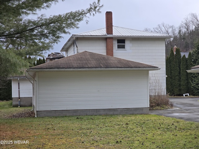 view of side of property featuring a chimney and a yard