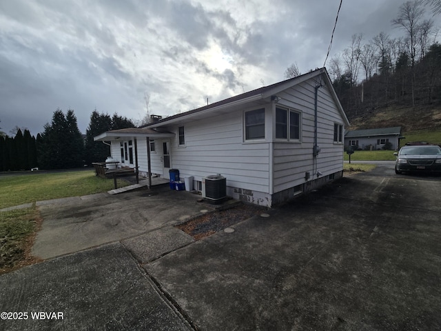 view of front of house with central air condition unit, driveway, and a front yard