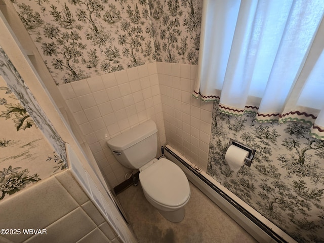 half bath with wainscoting, tile walls, toilet, and wallpapered walls