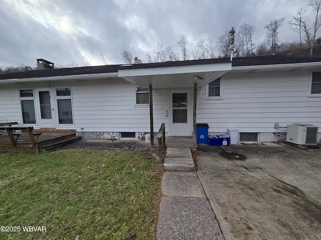 view of front of property featuring a patio, a chimney, cooling unit, and a front yard