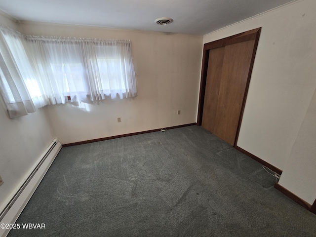 empty room with dark colored carpet, baseboard heating, visible vents, and baseboards