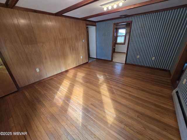 spare room with beam ceiling, wood walls, and wood-type flooring