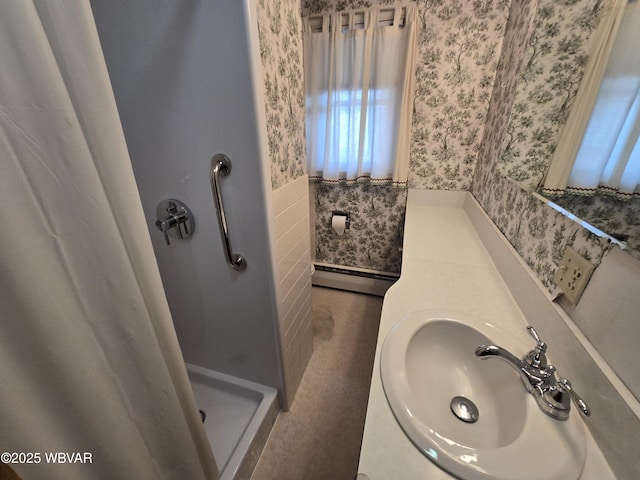 full bath featuring wallpapered walls, a stall shower, a wainscoted wall, a baseboard radiator, and a sink