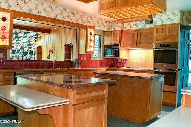 kitchen with decorative backsplash, a kitchen island, sink, and appliances with stainless steel finishes