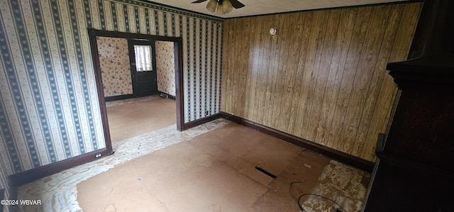 unfurnished room featuring ceiling fan and wooden walls